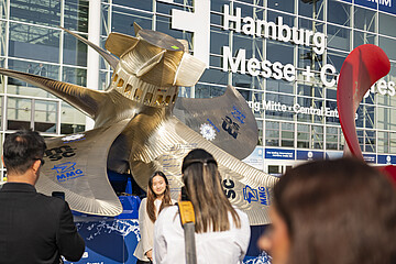 Großes Schiffspropeller‑Exponat vor dem Eingang der Hamburg Messe, mehrere Personen im Vordergrund; auf der Glasfassade steht „Hamburg Messe + Congress“.