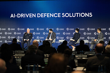 Podiumsdiskussion bei einer Konferenz mit dem Titel „AI-Driven Defence Solutions“, vier Personen auf einer Bühne vor Publikum.