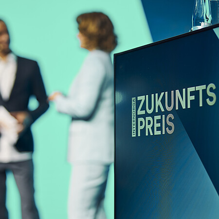 Verleihung des INTERNORGA Zukunftspreises auf der Bühne Podium mit dem Schriftzug „Zukunftspreis“ und zwei Personen im Hintergrund während einer Bühnensituation auf der INTERNORGA.