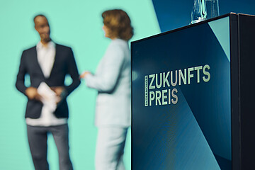 Podium mit dem Schriftzug „Zukunftspreis“ und zwei Personen im Hintergrund während einer Bühnensituation auf der INTERNORGA.